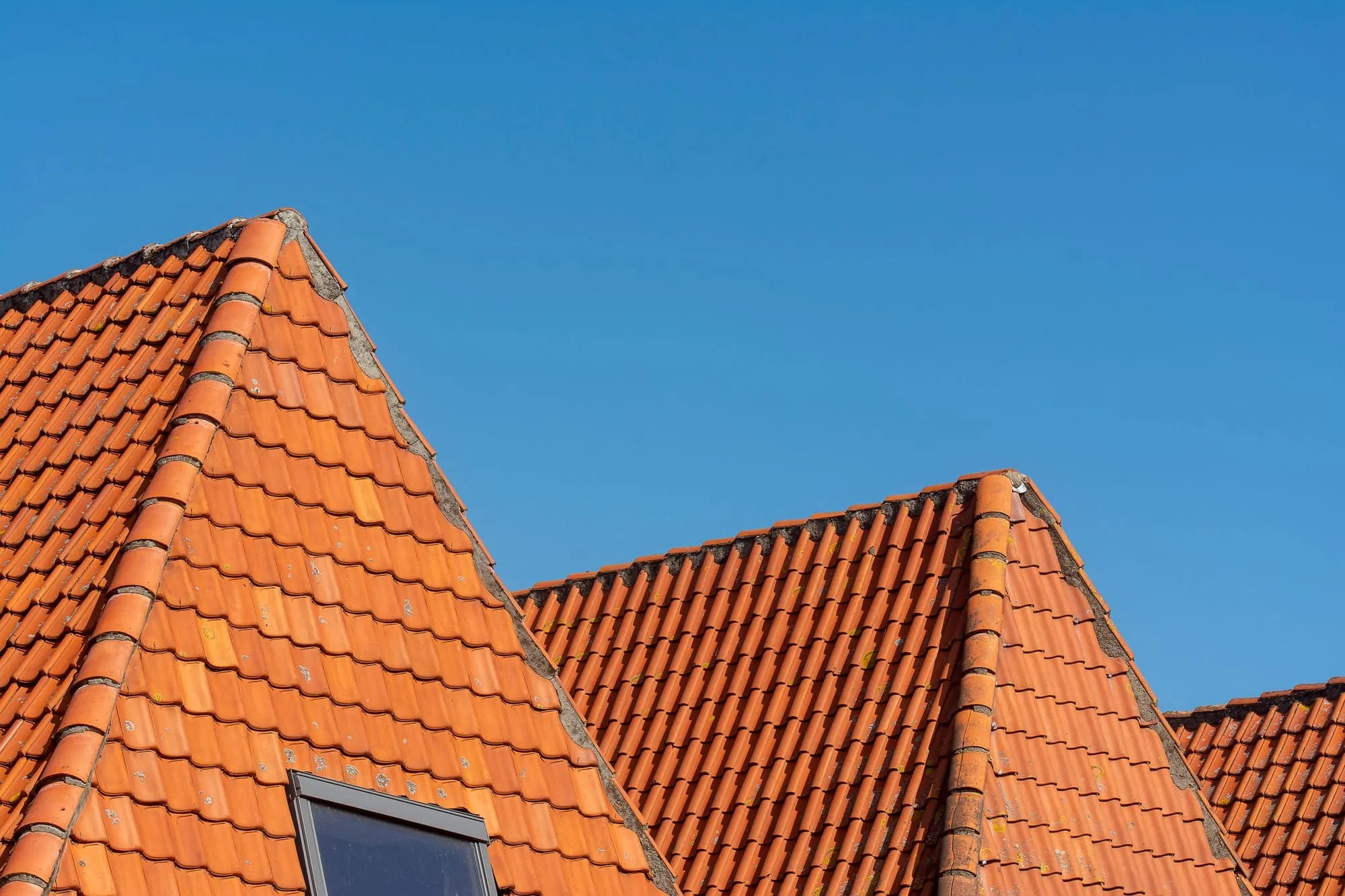 Rote Ziegeldächer mit spitzen Giebeln vor kräftig blauem Himmel